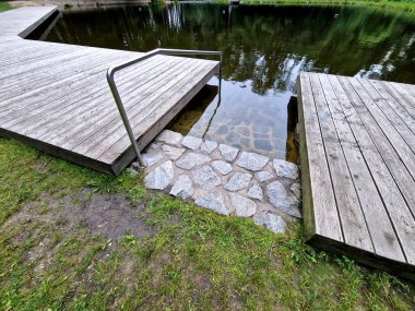 Gemileri demirlemek için yüzen bir iskele menteşeli metal çubuklarla sabitlenir. Ahşap merdivenler nehirdeki suyu gözlemlemek için kullanılır, Iris.