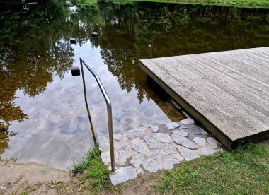 Gemileri demirlemek için yüzen bir iskele menteşeli metal çubuklarla sabitlenir. Ahşap merdivenler nehirdeki suyu gözlemlemek için kullanılır, Iris.