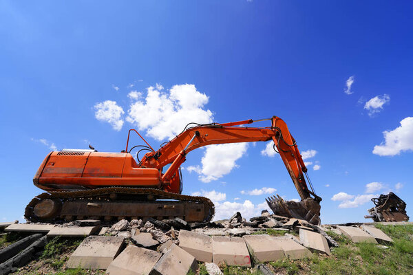 Экскаватор под голубым небом и белыми облаками