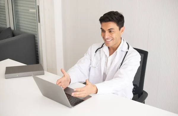 Hispanic physician wearing stethoscope in the clinic. Healthcare and medicine doctor working on laptop. Hospital specialist with medical examining.
