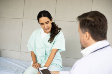 İspanyol kadın hastayla tablet üzerinde çalışan beyaz erkek doktor teşhisi. Diz sakatlığı. Tıbbi sağlık muayenesi ve doktor konseptiyle kontrol..