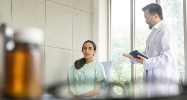 İspanyol kadın hastayla tablet üzerinde çalışan beyaz erkek doktor teşhisi. Tıbbi sağlık muayenesi ve doktor konseptiyle kontrol..