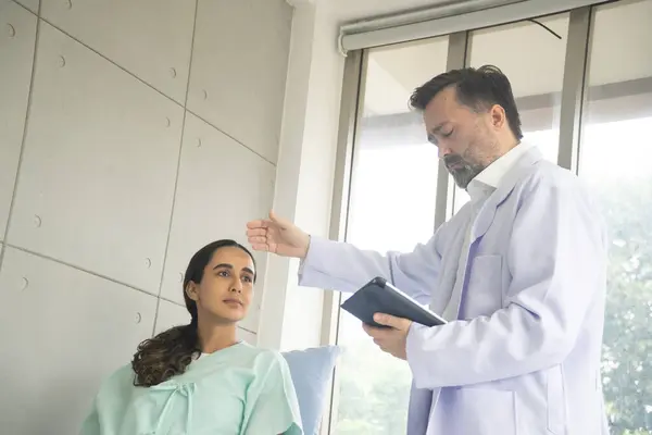Caucasian male physician diagnosis for root cause finding working on tablet with Hispanic female patient. The medical healthcare exam and check-up with the doctor concept.