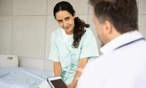 Caucasian male physician diagnosis for root cause finding working on tablet with Hispanic female patient. Knee injury problem. The medical healthcare exam and check-up with the doctor concept.