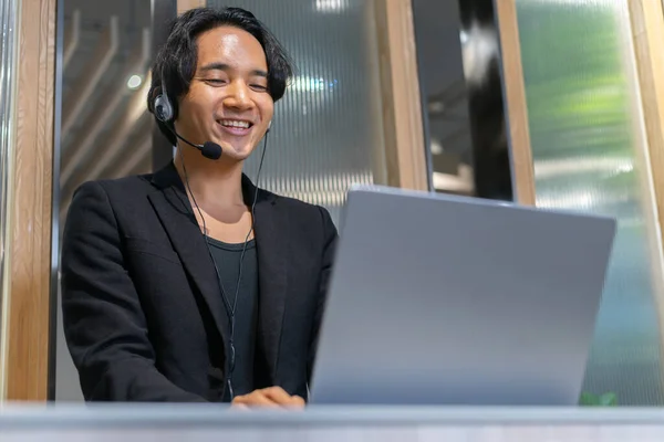 Customer service talking and helping the client. A call center of telemarketing business using headset, microphone and computer laptop while servicing the client.