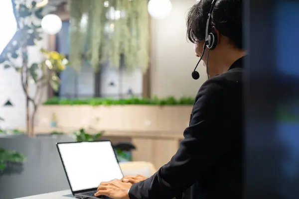 Customer service talking and helping the client. A call center of telemarketing business using headset, microphone and computer laptop while servicing the client.