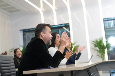 Bir grup farklı iş adamı beyin fırtınası sırasında ekip oluşturuyorlar. Ofisteki toplantı odasında başarılı bir proje için alkış tutan çok ırklı iş arkadaşları..