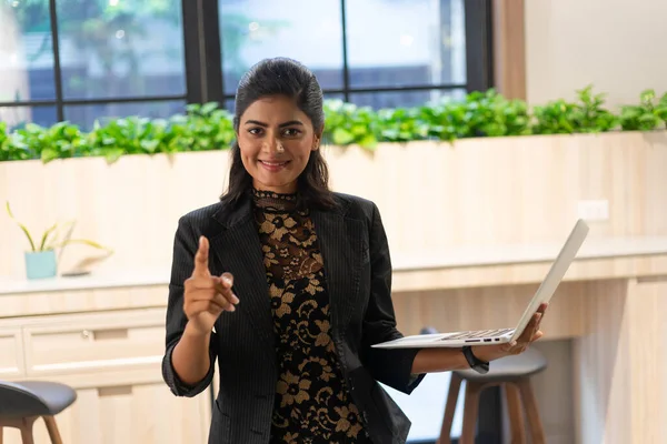Happy young Asian saleswoman holding laptop. Smiling business woman agent broker, Standing in the modern office. Successful posture portrait.