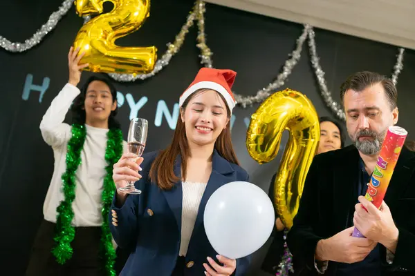 A group of business people and colleagues having fun together at a business New Year party. A teamwork celebration of a successful target. Confetti and wine glasses enjoyment.