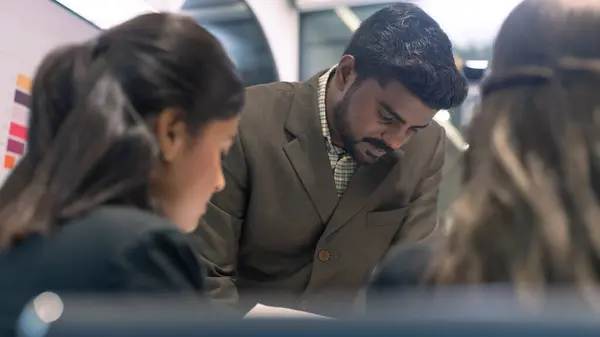 An Indian business boss giving briefs to team worker. Business communication in a teamwork meeting.