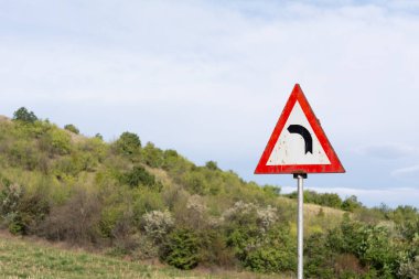 Tepeler ve bulutlu gökyüzü Romanya yolunda sola dönüş işareti