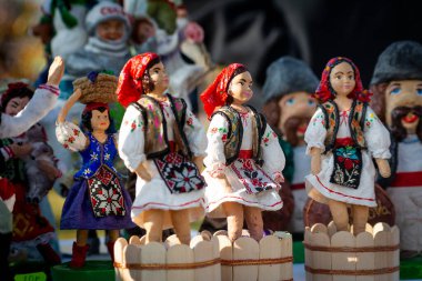 Geleneksel Moldova giysileri içinde kil hediyelik eşya çeşitleri. Ahşap buz pistinde üzümleri çiğneyen kadınların hatıra kil figürleri. Şarap Günü temalı Moldova halk sanatı. Halk sanatkarları fuarı