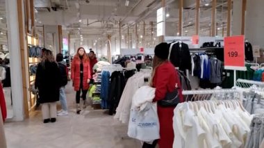 Chisinau, Moldova - 22 Kasım 2022: Alışveriş merkezi insanları. Alışveriş merkezindeki insanlar kıyafet seçiyor. Avrupalı kadınlar elbiseleriyle askılar arasında yürürler ve dış giysiyi seçerler.