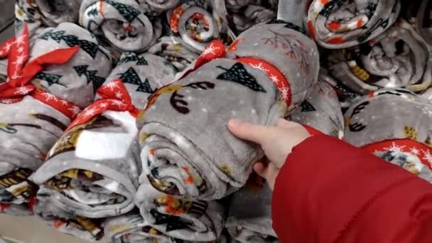 毛布を選びなさい 女性はクリスマス柄のフリースブランケットを選びます クリスマスをテーマに クリスマスのテーマのインテリアのための装飾 ハイパーマーケットでの家庭用織物の部門でのショッピング会った — ストック動画