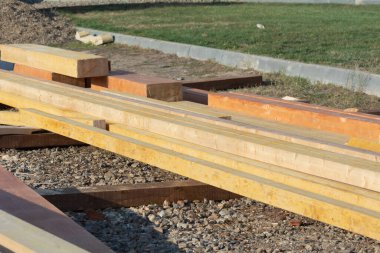 Kasımda inşaat alanında ahşap malzemeler var. Yakın çekim, seçici odaklanma. Ahşap tahtalar sıra sıra dizilip yere yatar. İnşaat tahtaları