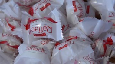 Chisinau, Moldova - December 24, 2022: Ferrero Raffaello Candies are rotating into plate. Raffaello is a coconut almond confection that manufactured by Ferrero. Selective focus, shallow depth of field