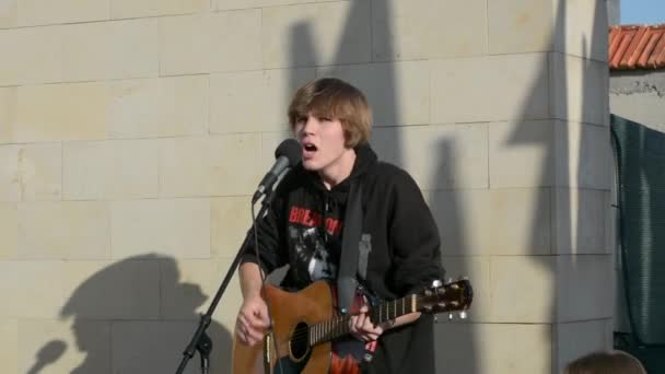摩尔多瓦 2022年11月12日 一个人在街上弹奏吉他和唱歌 一个长着金发碧眼的欧洲小伙子在街上弹吉他 在阳光灿烂的日子里歌唱 — 图库视频影像