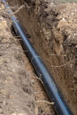 Plastic sewer pipe in trench for laying an external sewage system at a construction site.