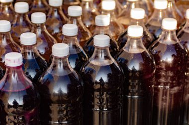 Şarap fuarında plastik bir şişede satılıyor. Kırmızı şarapla dolu sıra sıra plastik şişeler. Seçici odak, yüzeysel alan derinliği