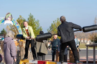 Bendery, Moldova - 12 Kasım 2022: kütük güreşi oyunu. Maslenitsa bayramındaki şenlikler. Oyunun amacı diğerini kayıt dışı tutmaktır..