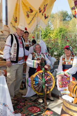 Bender, Moldova - 21 Ekim 2023: Bulgaristan 'ın ulusal kostümlü yaşlı erkek ve kadınları, eski nitelikleri, dönen halılar, havlular. Şarap Festivali 'nde halk sanatı sergisi