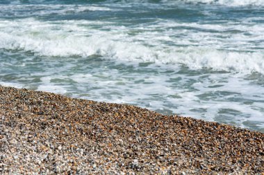 Kıyıya vuran hafif dalgalarla dolu bir çakıl taşı sahili sakin bir sahil manzarası yaratıyor. Mamaia plajı, Constanta, Romanya
