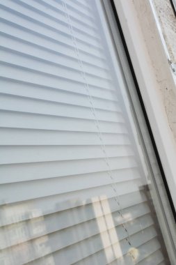 Dışarıdan plastik bir pencere görünüyor. Plastik bir pencerenin perdeleri. Seçici odak, yüzeysel alan derinliği.