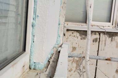 Binanın ön cephesine mavi köpüklü polistiren köpük sürüyorum. Bir apartmanın dış cephesinin izolasyonu. Dış cepheyi polistiren köpükle yalıtım için hazırlıyorum. Seçici odak, yüzeysel alan derinliği