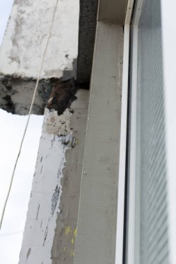 Ön cephenin köpük plastikle izolasyonu. Pencerenin etrafındaki yamaçları ve köşeleri havan topu ve çimentoyla kaplıyor. Seçici odak, yüzeysel alan derinliği