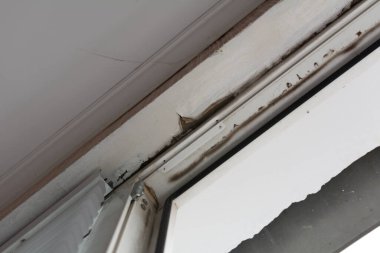 Pencere çerçevesi ile tavan arasında yağmur damlıyor. Kötü onarımdan dolayı çatı hasarı.