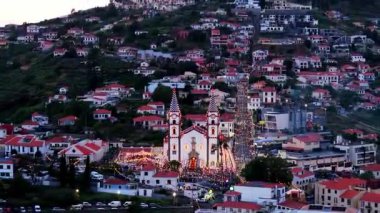 Portekiz, Madeira, Funchal 'daki tarihi bir kiliseyi çevreleyen hava aracı görüntüleri. Klipte, şehrin büyüleyici kentsel manzarasıyla çevrili kırmızı kiremitli çatıları olan geleneksel Portekiz mimarisi sergileniyor.. 
