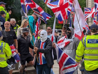 Manchester, İngiltere, 2 Ağustos 2025. İngiltere 'nin kentteki ilk protesto yürüyüşü, şehir merkezinde, polis ve maskeli protestocular eşliğinde sendika bayrakları ve sağ görüşlü protestocuları gösteriyor.