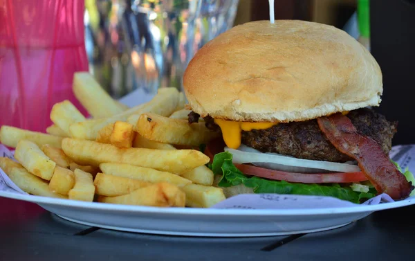 full burger, hamburger with bacon cheese, tomato and french fries from a restaurant