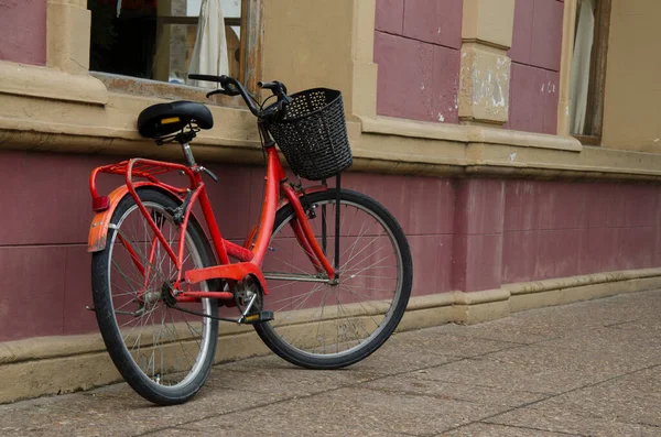 Stary Czerwony Rower Opierający Się Trawie Przed Budową Domu Miejskiego — Zdjęcie stockowe