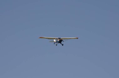 Hafif uçak arka planda mavi gökyüzü ile kafa kafaya uçuyor.