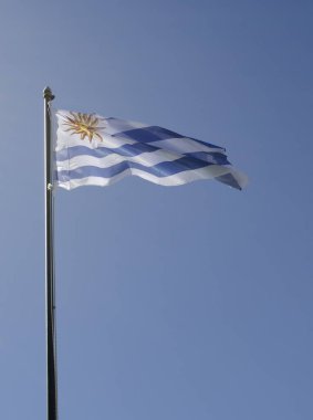 Uruguay bayrağı mavi ve beyaz, arka planda mavi gökyüzü var.