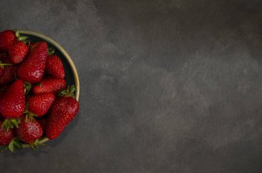 Yuvarlak seramik kabın içindeki taze kırmızı böğürtlenler gri arkaplan üzerinde üst görünüm doldurmak için boşluk