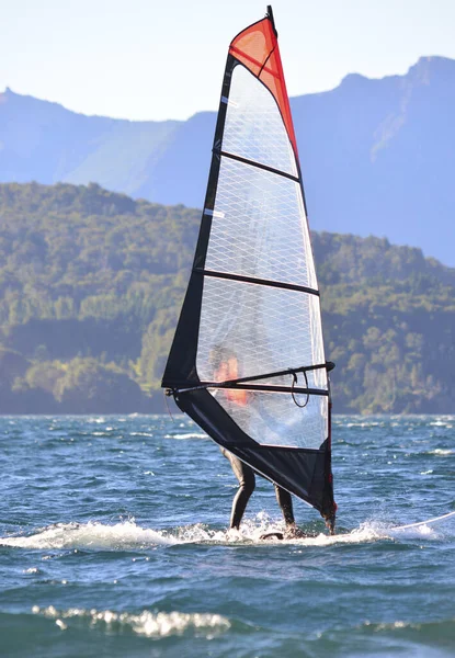 windsurfing on a lake. windsurfer going upwind doing water sports with mountains in the background
