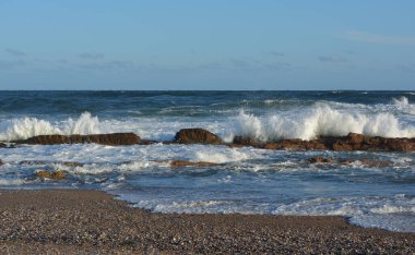 Deniz kıyısında dalgalar kopuyor.