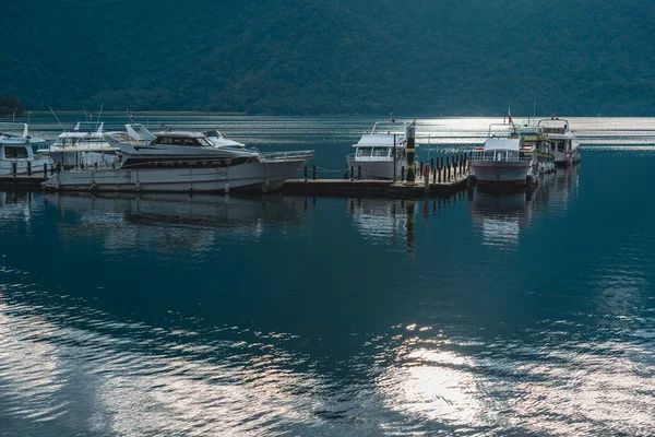 Some boats on the lake are docked at the wooden pier. The lake is very calm. Chaowu Pier, Sun Moon Lake National Scenic Area. Nantou County, Taiwan