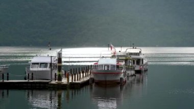 Göldeki bazı tekneler ahşap rıhtıma yanaştı. Göl çok sakin. Chaowu İskelesi, Sun Moon Gölü Ulusal Sahne Bölgesi. Nantou İlçesi, Tayvan