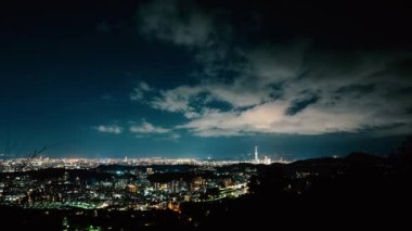 Kulenin tepesindeki mavi lazerlerden gelen ışık her yöne doğru parlıyor. Dağlarla çevrili şehrin gece manzarası sisli ve rüya gibi Taipei City, Tayvan