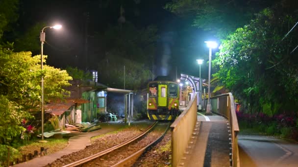 山の中の小さな駅がライトアップされます 黄色の列車がゆっくりと出てくる 台湾新北市サンディエオリン鉄道駅 — ストック動画