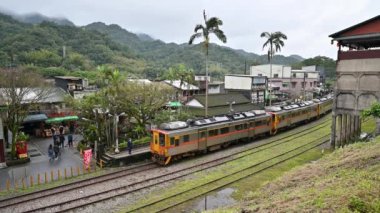 Sarı tren istasyon platformunun yanında park edilmiştir. Tepede küçük bir istasyon. Jingtong İstasyonu, Tayvan 'ın New Taipei şehrindedir..