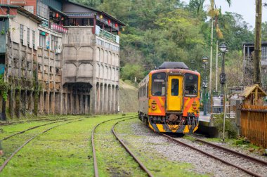 Sarı tren istasyon platformunun yanında park edilmiştir. Tepede küçük bir istasyon. Jingtong İstasyonu, Tayvan 'ın New Taipei şehrindedir..