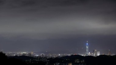 Geceleri gökyüzünde bulutlar hareket ediyor. Neon ışıkları canlı şehir manzarasında parlıyor. Şehrin puslu ve rüya gibi gece manzarası. Taipei Şehri, Tayvan
