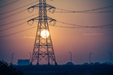 Alacakaranlıkta güç dolu bir günbatımının görüntüsü. Ön planda yüksek voltajlı elektrik kuleleri var. Marsonda Köprüsü, Tainan Şehri, Tayvan