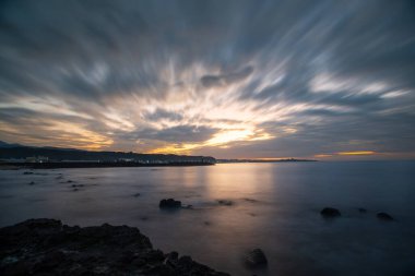 Dynamic fast moving clouds and red sunset. rocky coast. The view of the sea at dusk. Shimen District, New Taipei City, Taiwan