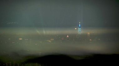 Clouds moving in the sky at night. Neon lights shine on the vibrant cityscape. Hazy and dreamy city night view. Lion's Head Mountain, New Taipei City, Taiwan