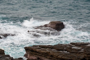 White waves lapping on the rocks. A symbol of hard work and strength. Ruifang Rocky Beach, New Taipei City, Taiwan.